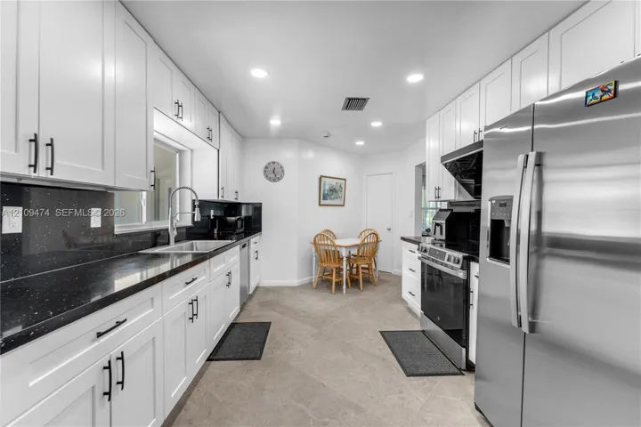 Kitchen featuring white shaker-style cabinetry, contrasting dark countertops, tile flooring, recessed lighting, and stainless steel appliances