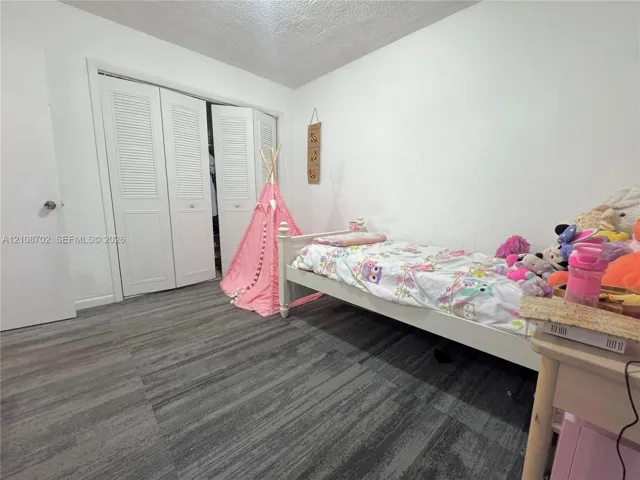 Room featuring wood-finish flooring and a closet with white louvered bi-fold doors