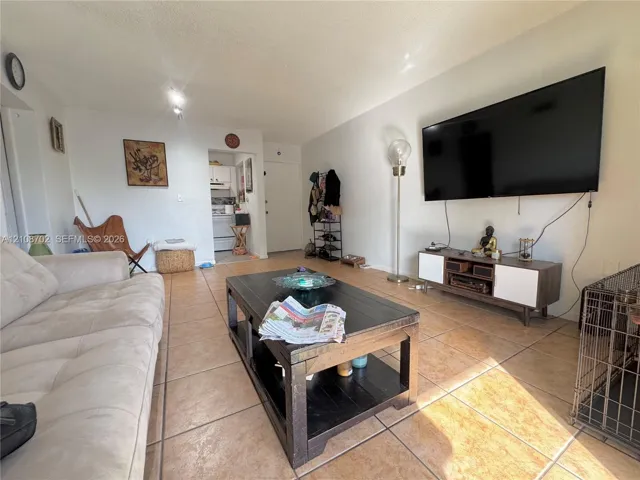Neutral-toned living space featuring large-format tile flooring and overhead recessed lighting