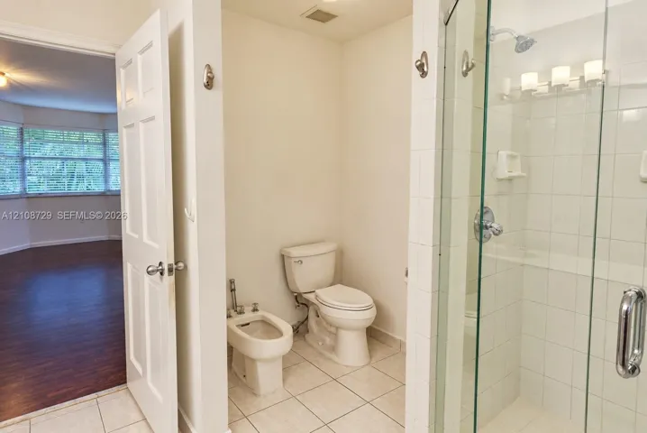 Bathroom featuring a glass-enclosed shower with white wall tile, a bidet, a ceramic toilet, and large-format tile flooring