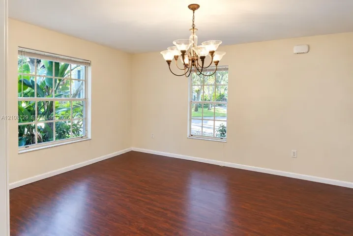 Room featuring wood-laminated flooring, multi-pane windows, and a multi-arm metal chandelier with glass shades
