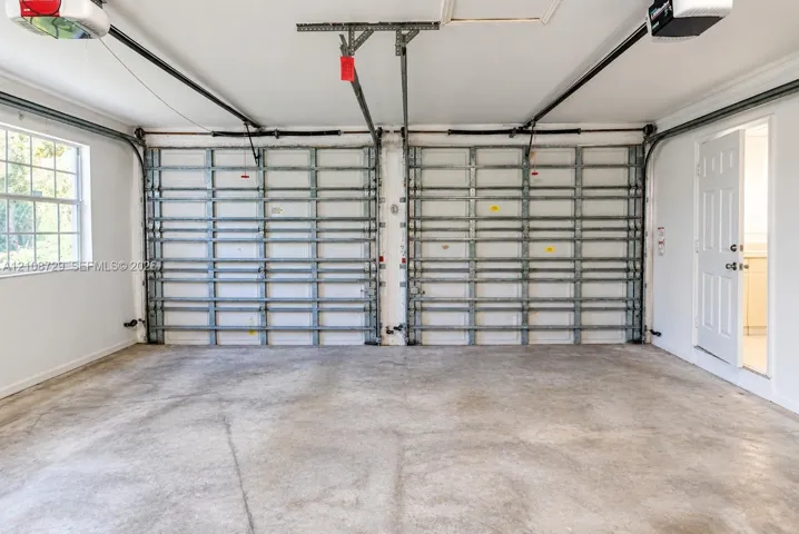 Two-car garage featuring dual overhead doors, concrete flooring, automatic openers, and a multi-pane window