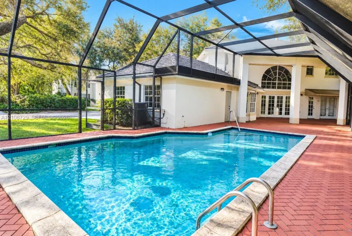 Screened-in outdoor area featuring a swimming pool, red brick paver decking, and an arched transom window
