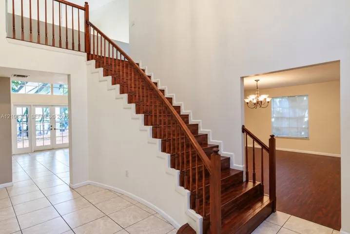 Foyer featuring a double-height ceiling, ceramic tile flooring, and a wooden staircase with decorative railings