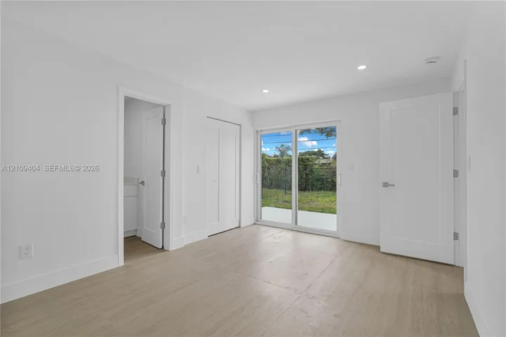 Interior featuring wood-finish flooring, recessed lighting, white shaker-style interior doors, and sliding glass patio doors