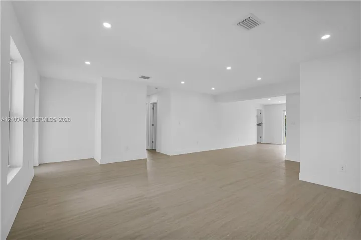 Open-concept interior featuring wood-finish flooring, recessed lighting, and crisp white wall finishes