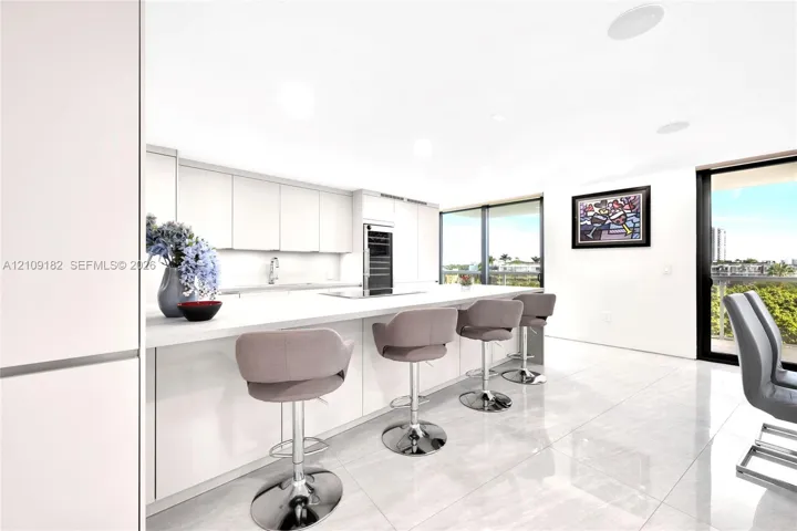 Contemporary kitchen featuring flat-panel cabinetry, a spacious island with a solid-surface countertop, integrated wine refrigeration, and large-format tile flooring