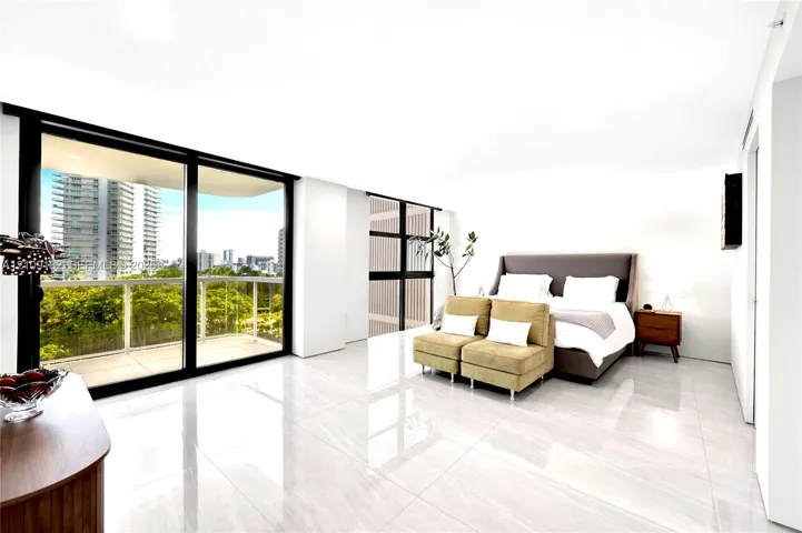 Floor-to-ceiling sliding glass doors, large private balcony with metal railing, polished stone-finish flooring, and expansive window lines