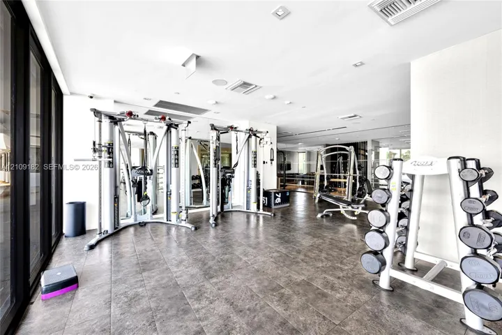 Fitness center featuring large-format tile flooring, wall-to-wall mirrors, recessed lighting, and expansive floor-to-ceiling glass paneling