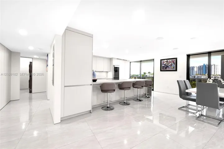 Contemporary kitchen featuring flat-panel cabinetry, a stone-surfaced kitchen island, integrated appliances, and large-format tile flooring