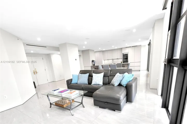 Open-concept floor plan featuring large-format polished tile flooring, floor-to-ceiling windows with dark framing, recessed lighting, and built-in minimalist cabinetry