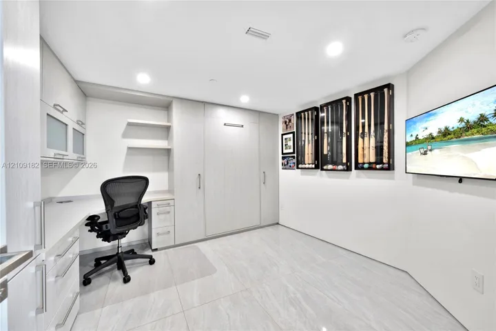 Custom built-in light-tone cabinetry, integrated wall-mounted desk, recessed LED lighting, and neutral large-format tile flooring