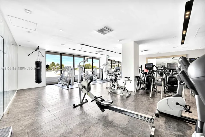 Fitness center featuring large-format tile flooring, floor-to-ceiling glass walls, and recessed lighting