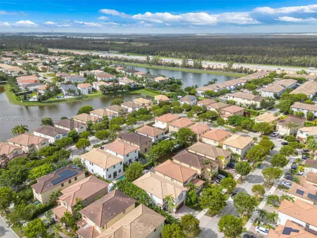 Aerial perspective of a planned community featuring tiled-roof residential structures, mature landscaping, and waterfront areas