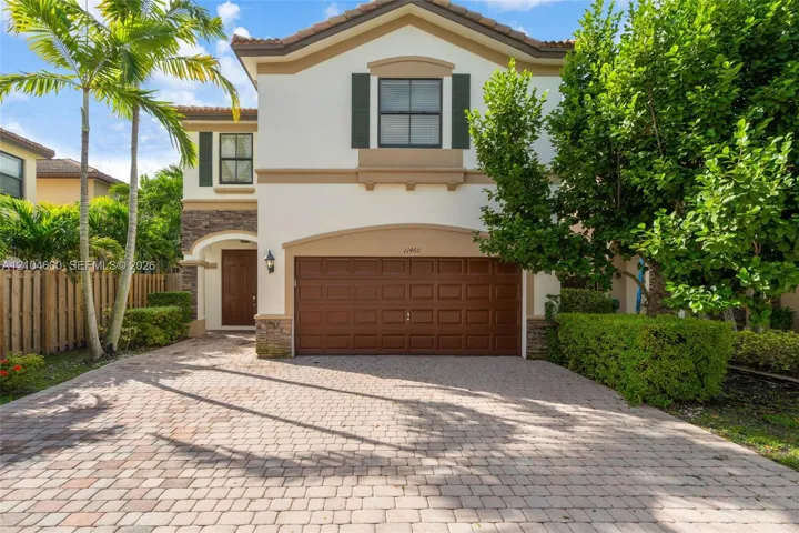 Two-story exterior featuring a paver driveway, stone veneer accents, a tiled roof, and a multi-panel garage door