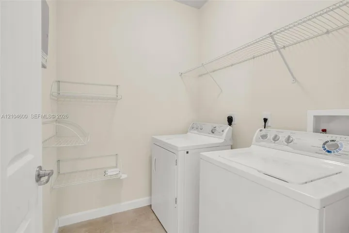 Laundry area featuring built-in wire shelving and tile flooring