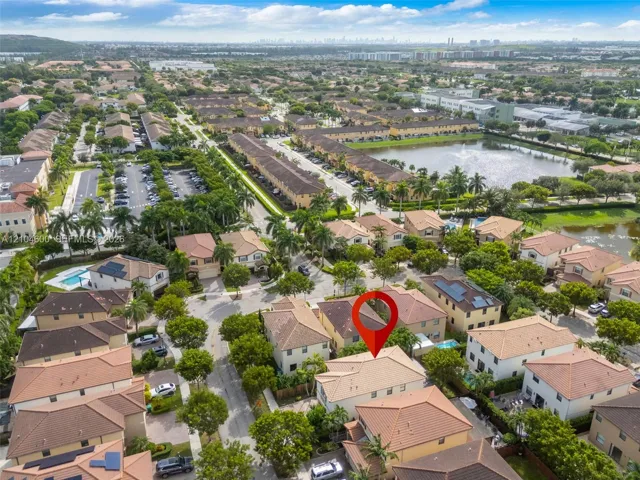 Aerial perspective of a multi-unit residential community featuring tile roofing, stucco exterior finishes, and mature landscaping