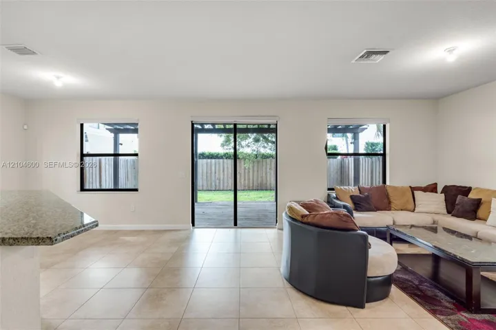 Open-concept room featuring light-toned tile flooring, recessed lighting, and a stone-surface breakfast bar