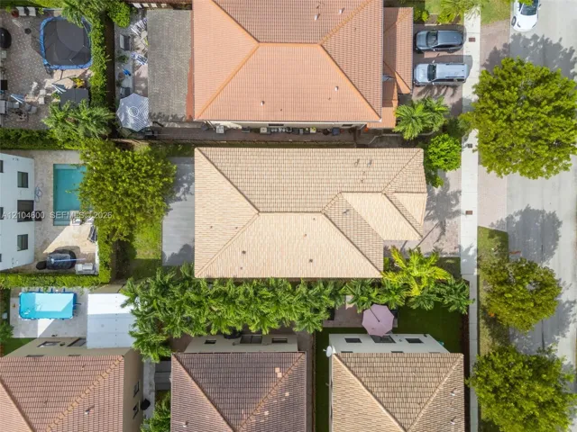 Aerial view of property featuring a multi-pitched tile roof and mature palm tree landscaping