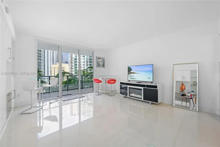 Living area featuring large-format tile flooring, floor-to-ceiling glass sliding doors, and built-in cabinetry