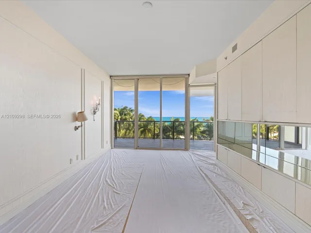 Full-height wall paneling, built-in cabinetry with mirrored backsplash, and floor-to-ceiling glass sliding doors opening to a covered balcony