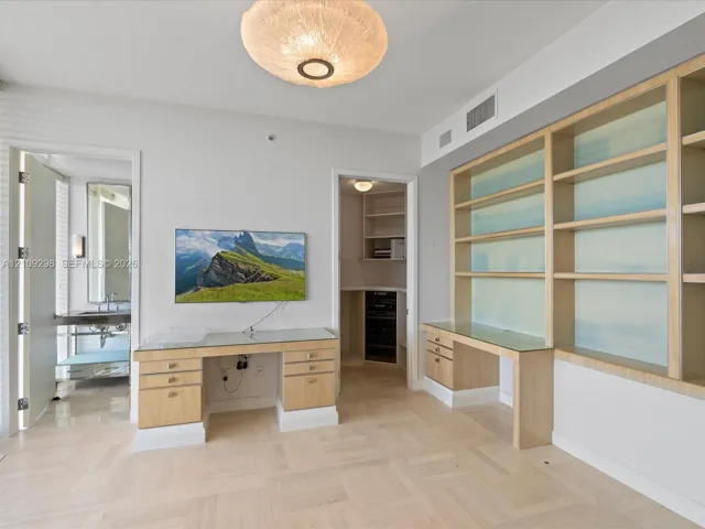 Custom light wood cabinetry with built-in desk surfaces, integrated shelving, flush-mount circular lighting, and parquet wood-finish flooring