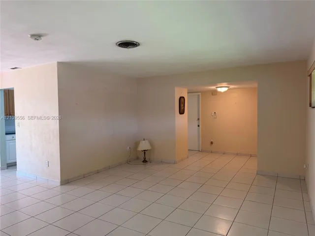 Neutral-toned interior space featuring ceramic tile flooring, a flush-mount ceiling light fixture, and white interior doors