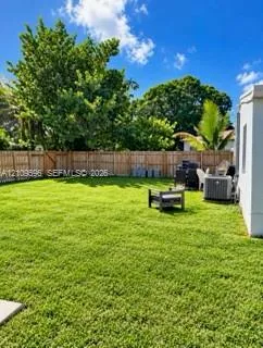 Backyard featuring a manicured lawn, privacy wood fencing, and mature trees