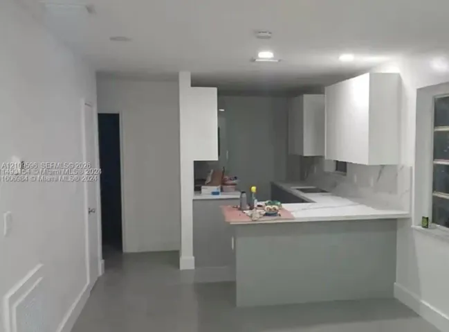 Kitchen featuring white shaker-style cabinetry, a stone-finish countertop, a peninsula breakfast bar, and recessed ceiling lighting