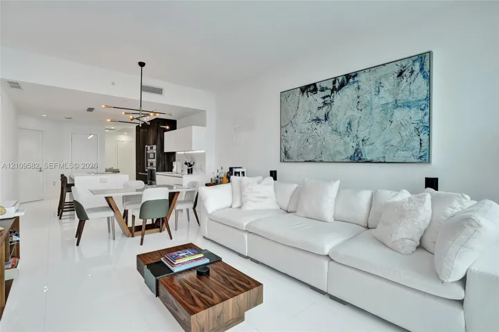 Open-concept area featuring polished white tile flooring, modern multi-arm sputnik chandelier, and high-gloss cabinetry