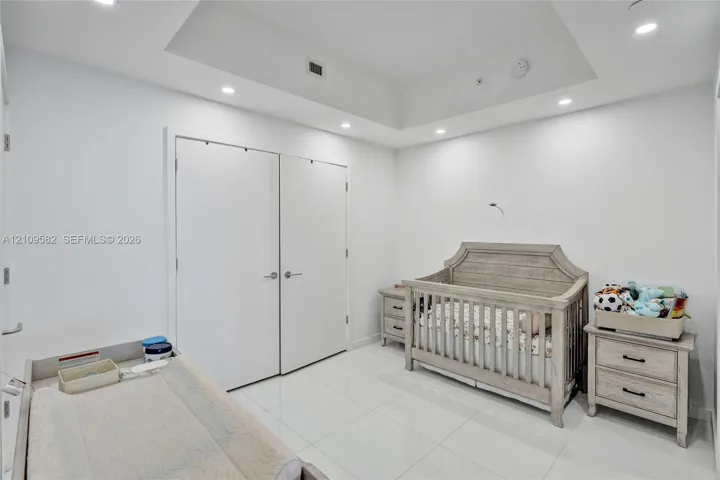 Interior space featuring high-gloss tile flooring, a recessed tray ceiling, integrated recessed lighting, and a double-door reach-in closet