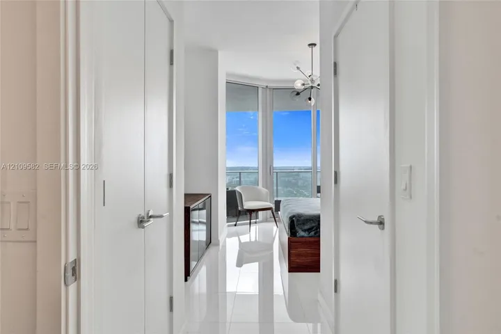 Floor-to-ceiling windows, polished tile flooring, multi-arm chandelier, and double-closet configuration