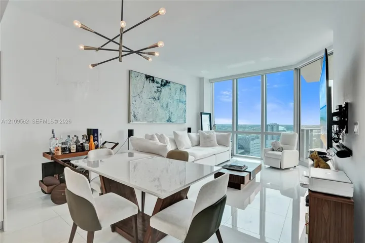 Floor-to-ceiling windows, polished tile flooring, contemporary multi-arm chandelier, and open-concept layout