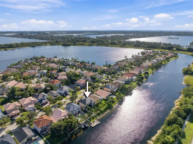 Aerial perspective of a waterfront residential property featuring a private boat dock and tile roofing