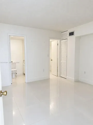 Polished tile flooring, neutral wall finishes, and floor-to-ceiling louvered closet doors