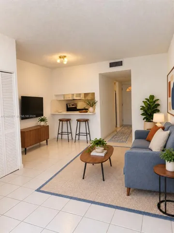 Open-concept interior featuring white ceramic tile flooring, a breakfast bar, and louvered closet doors
