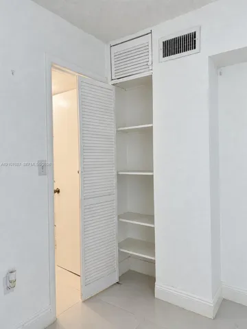Built-in storage cabinet featuring adjustable shelving and a louvered door