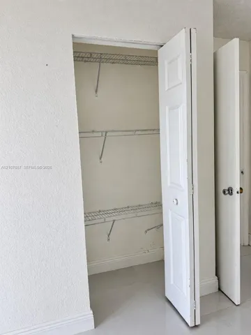Storage closet featuring bi-fold doors and three-tier wire shelving