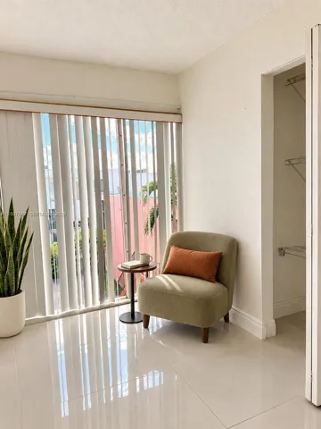 Neutral tile flooring, floor-to-ceiling vertical blinds, and a built-in closet with wire shelving