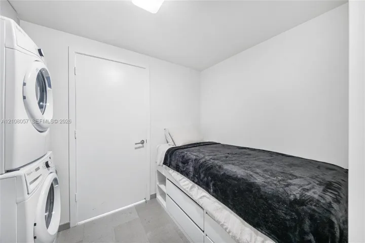 Stacked laundry unit, built-in platform cabinetry with integrated shelving, and solid-core door with contemporary hardware