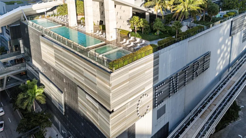 Rooftop terrace featuring an elevated swimming pool, spa, manicured landscaping, and contemporary panelized building facade