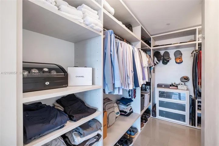 Walk-in closet featuring extensive built-in shelving, integrated hanging rods, and built-in drawer units with glass-front detailing