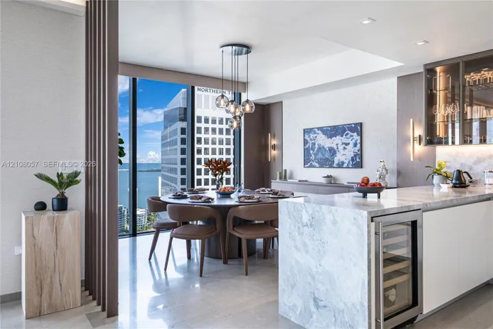 Kitchen featuring a stone waterfall island with integrated wine refrigeration, floor-to-ceiling windows, custom slat wood room divider, recessed lighting, and glass-front cabinetry