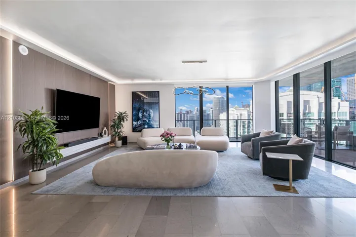 Living area featuring floor-to-ceiling windows, wood-paneled accent wall, recessed perimeter lighting, custom floating media console, and large-format tile flooring