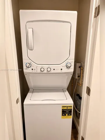 Stacked white laundry unit featuring a top-loading washer, front-loading dryer, and tactile control knobs