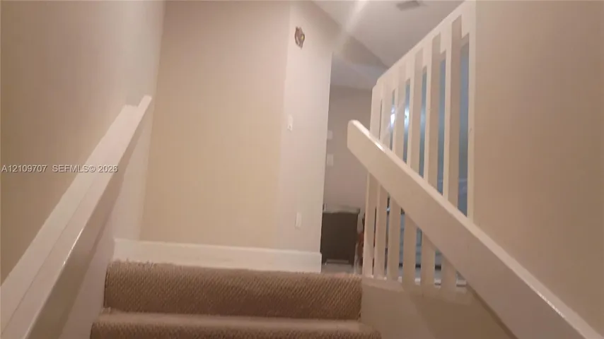 Staircase featuring wall-mounted railings and a vertical baluster handrail system
