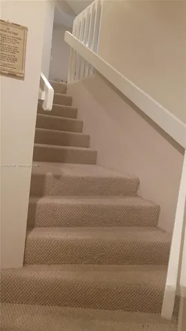 Staircase featuring wall-to-wall carpeting, white painted handrails, and vertical balusters