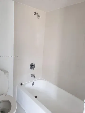 Full-size bathtub with integrated shower, polished chrome single-handle faucet, and floor-to-ceiling tile surround