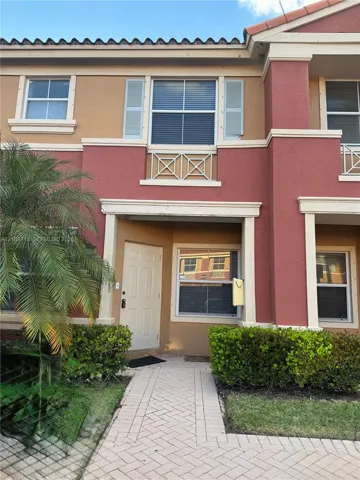 Two-story exterior featuring a clay tile roof, decorative shutters, upper-level balcony railing, and a paved walkway
