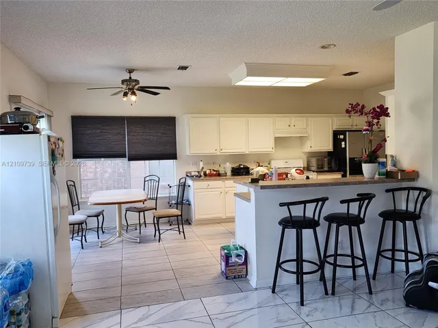 Kitchen featuring white cabinetry, a breakfast bar, recessed lighting, and large-format floor tiling